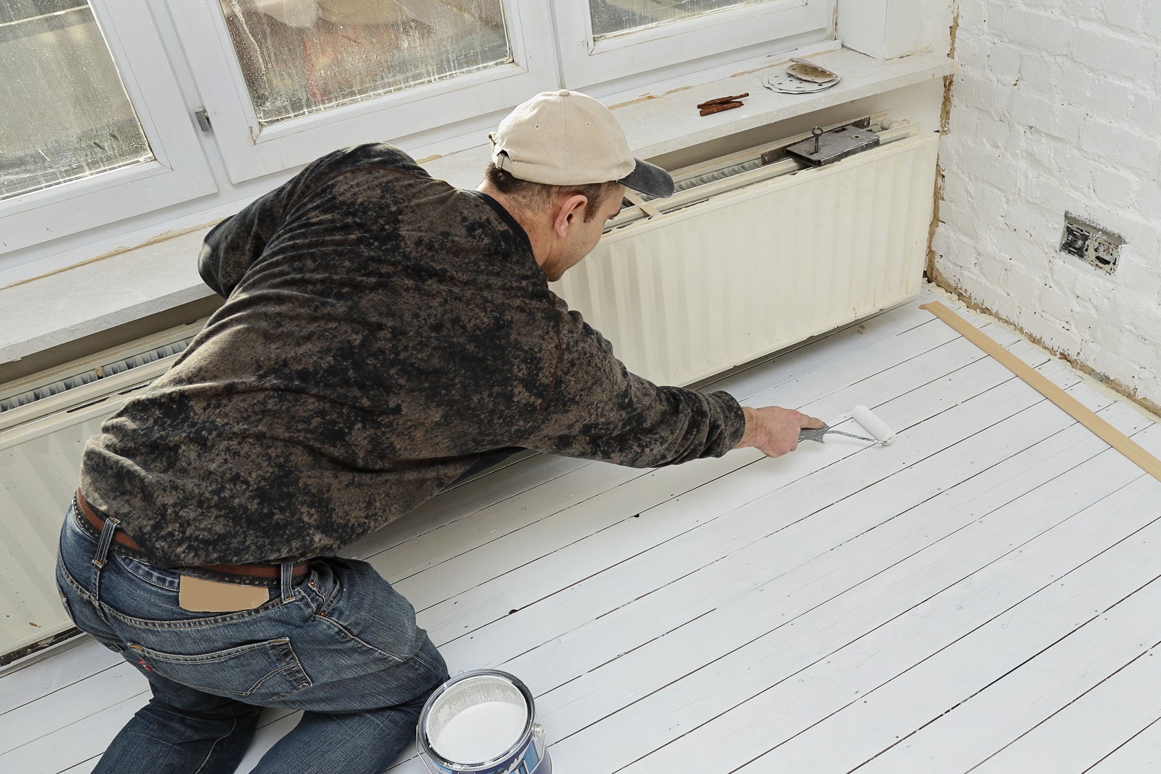 Artisan posant de la peinture sur du parquet