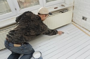 Artisan peignant parquet.